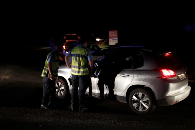 Police stop a car at a roadblock a certain distance from the scene where a car ploughed into the outdoor terrace of a pizzeria in Sept-Sorts